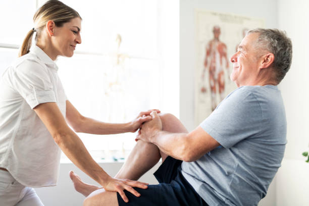 Physiotherapist helping elderly with leg exercise